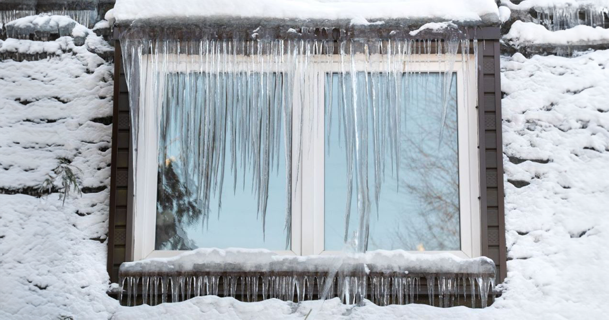 Ice dam and icicles draping down window on home. 