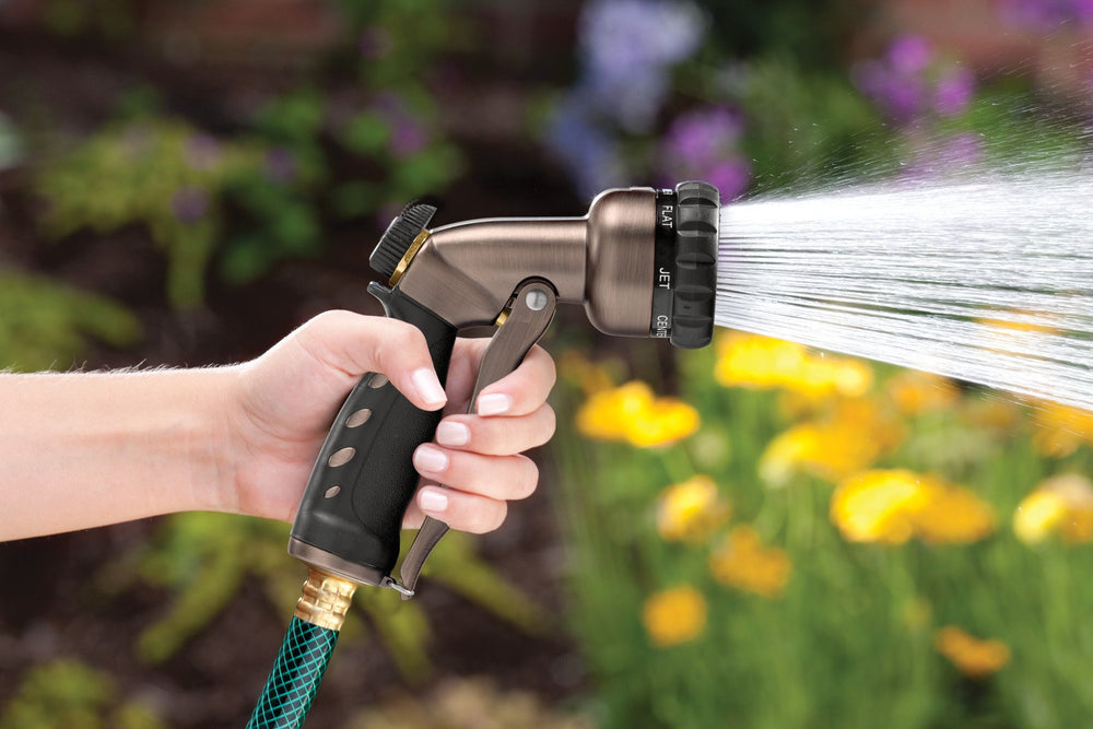 Bronze colored seven pattern zinc front trigger nozzle emitting a full spray pattern of water.