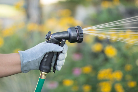 Graphite colored seven pattern zinc front trigger nozzle emitting a cone spray pattern of water. 