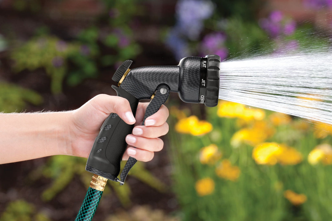 Graphite colored seven pattern zinc front trigger nozzle emitting a full spray pattern of water.