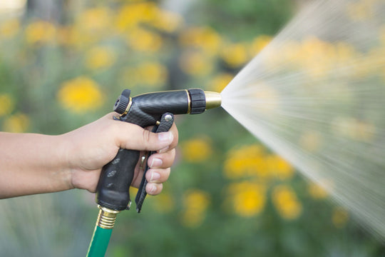 Graphite colored adjustable zinc front trigger nozzle, emitting a full spray pattern of water.