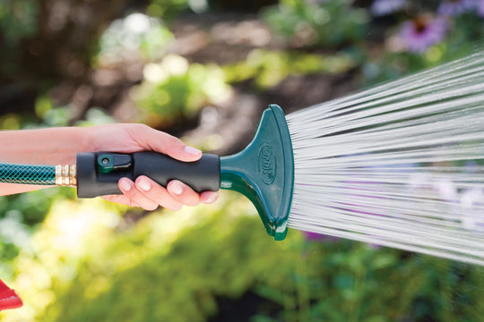 Aluminum fan spray shower nozzle with shut-off lever, emitting a spray of water.